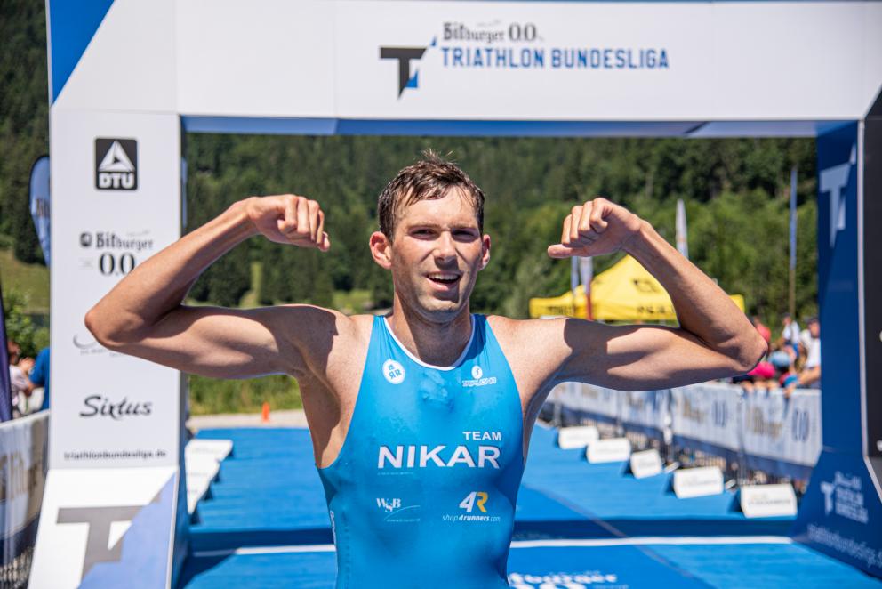 Athlet von Nikar Heidelberg posiert vor im Ziel mit seinen Muskeln. 