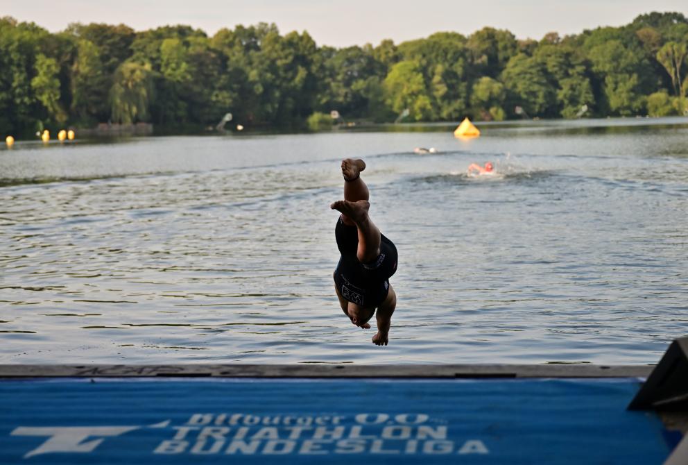 Ein Triathlet springt Kopfüber ins Wasser. 