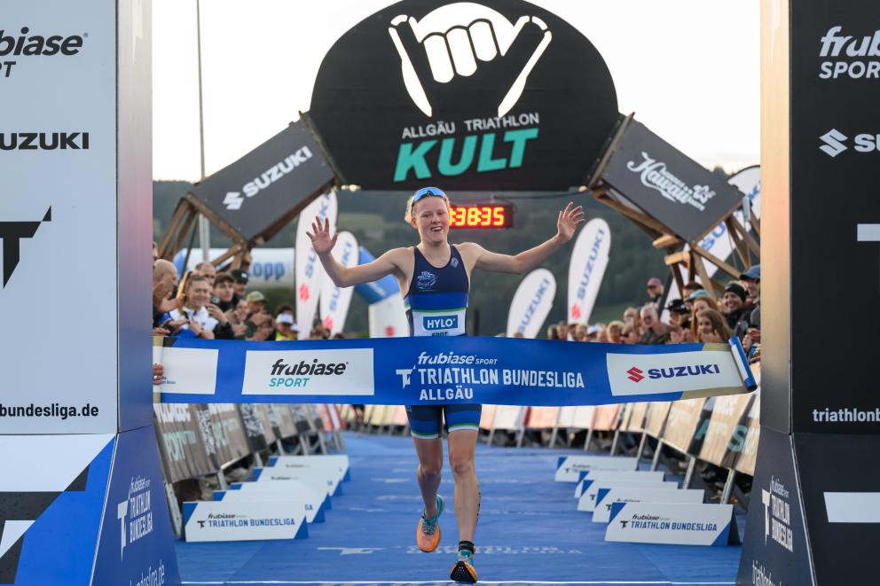 Eine Triathletin läuft jubelnd als Siegerin über die Ziellinie