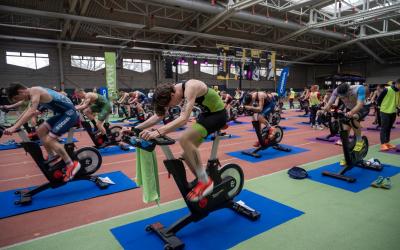 viele Sportler sitzen auf Ergometern und treten in die Pedalen