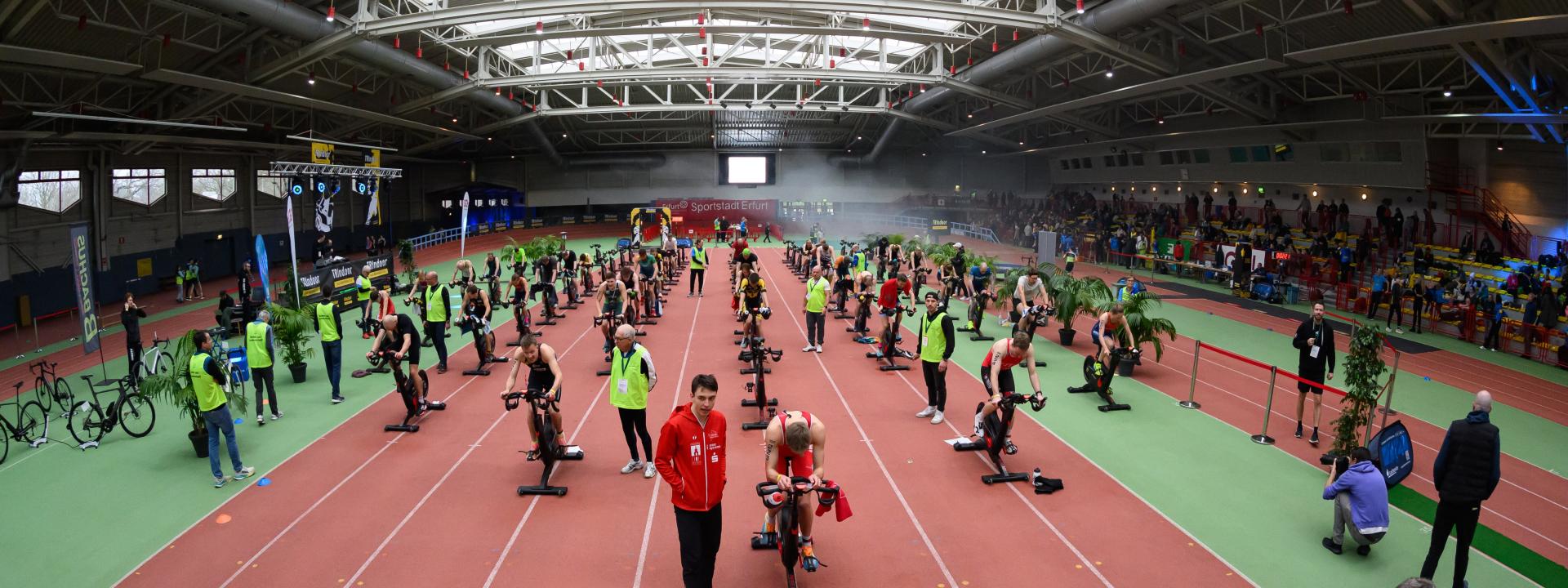 in einer Sporthalle treten mehrere junge Athleten auf Rollentrainern gegeneinander an