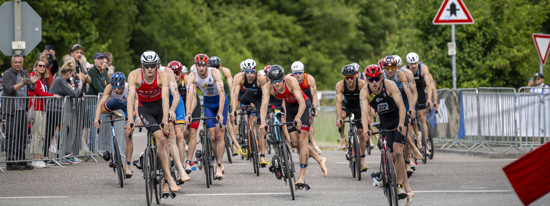 Gruppe von Triathleten fahren in die Wechselzone, bereit zum Absteigen