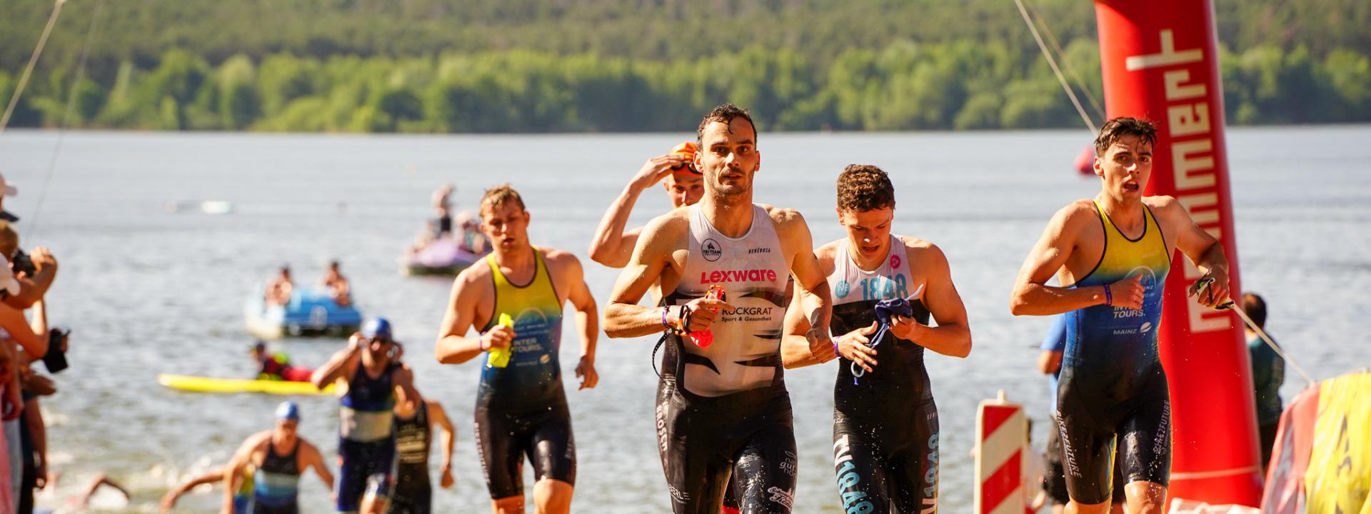 Athleten kommen aus dem Wasser und laufen den Strand hoch