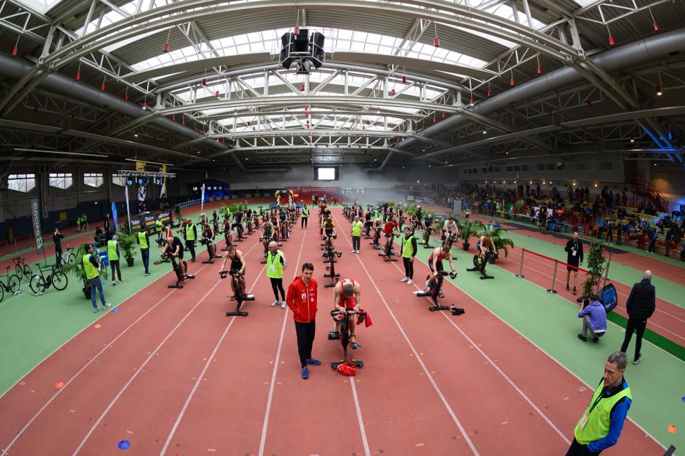 in einer Sporthalle treten mehrere junge Athleten auf Rollentrainern gegeneinander an