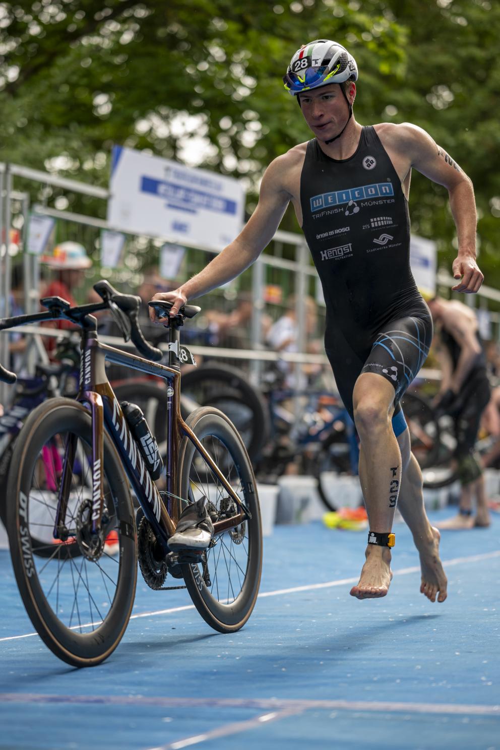 Triathlet von Münster schiebt sein Rad durch die Wechselzone