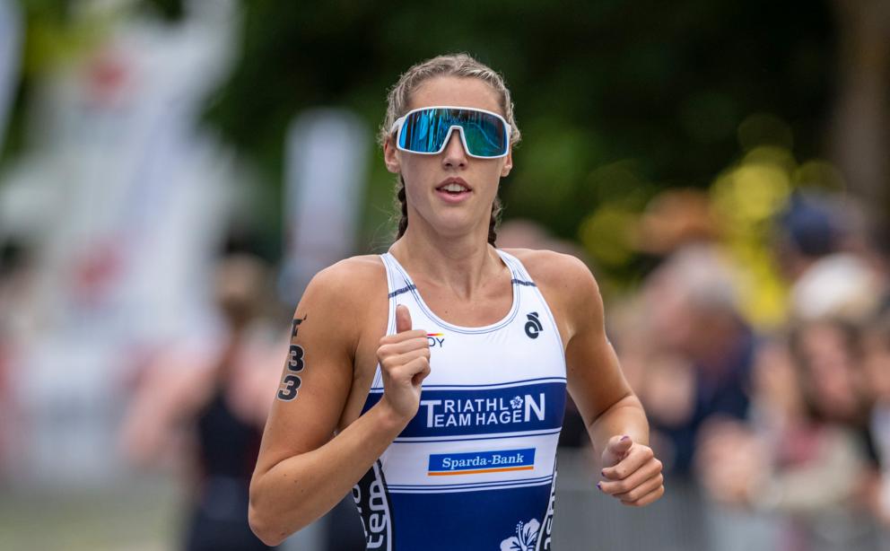 Athletin aus Team Hagen läuft in einem weiß-blauen Triusuit auf die Kamera zu