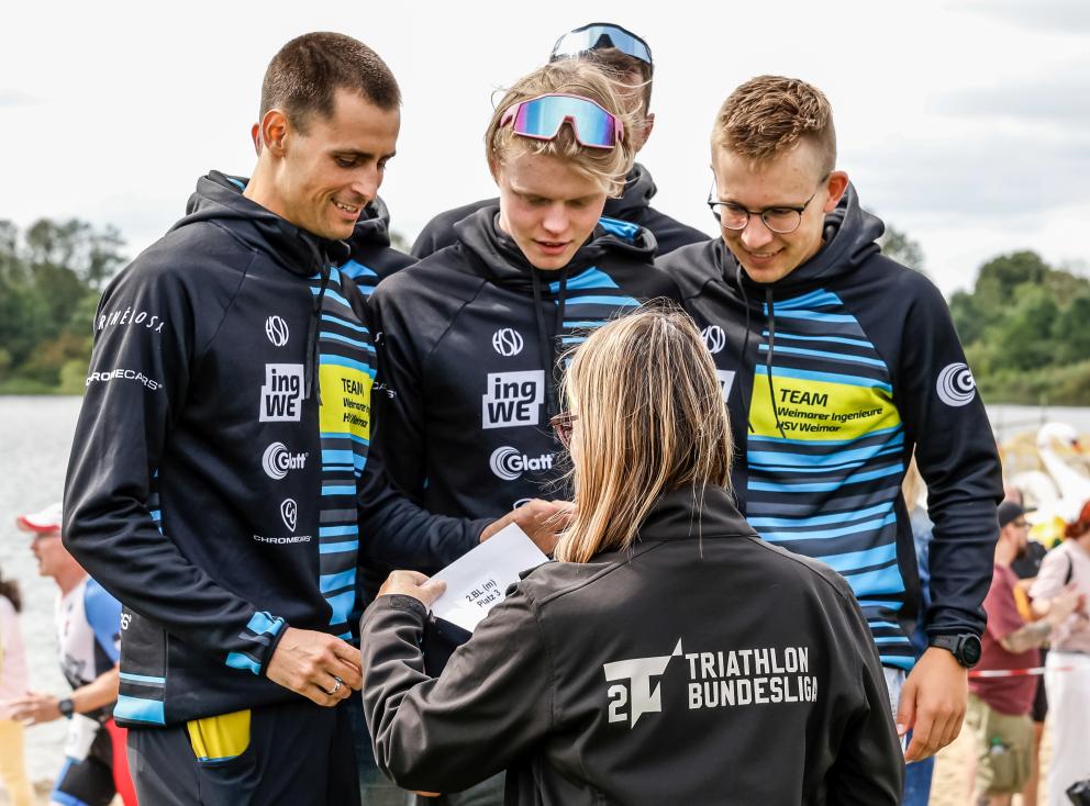 Frau von hinten in 2. Triathlon Bundesliga Jacke bei der Ehrung von fünf Männern