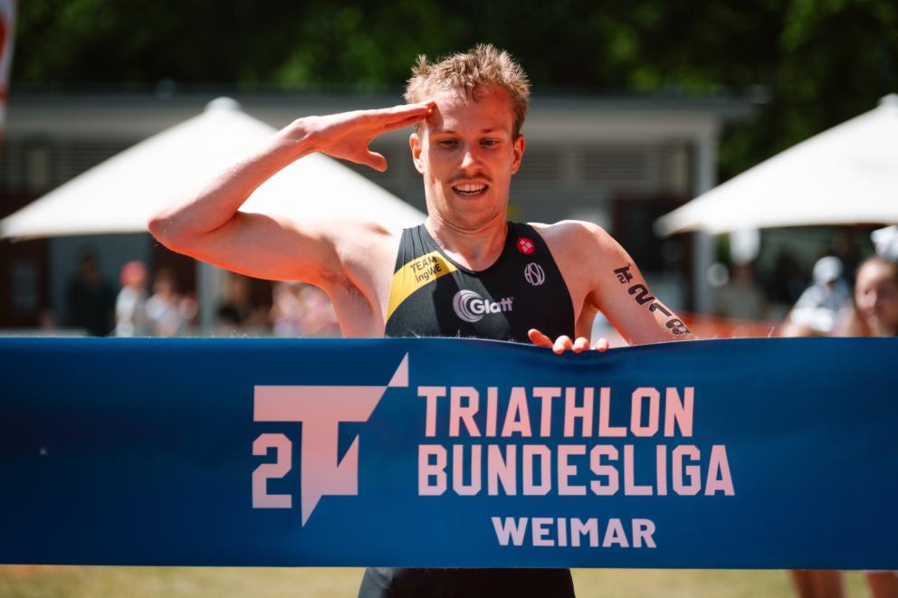 Athlet der 2. Liga läuft auf Zielbanner hoch macht Militärgruß