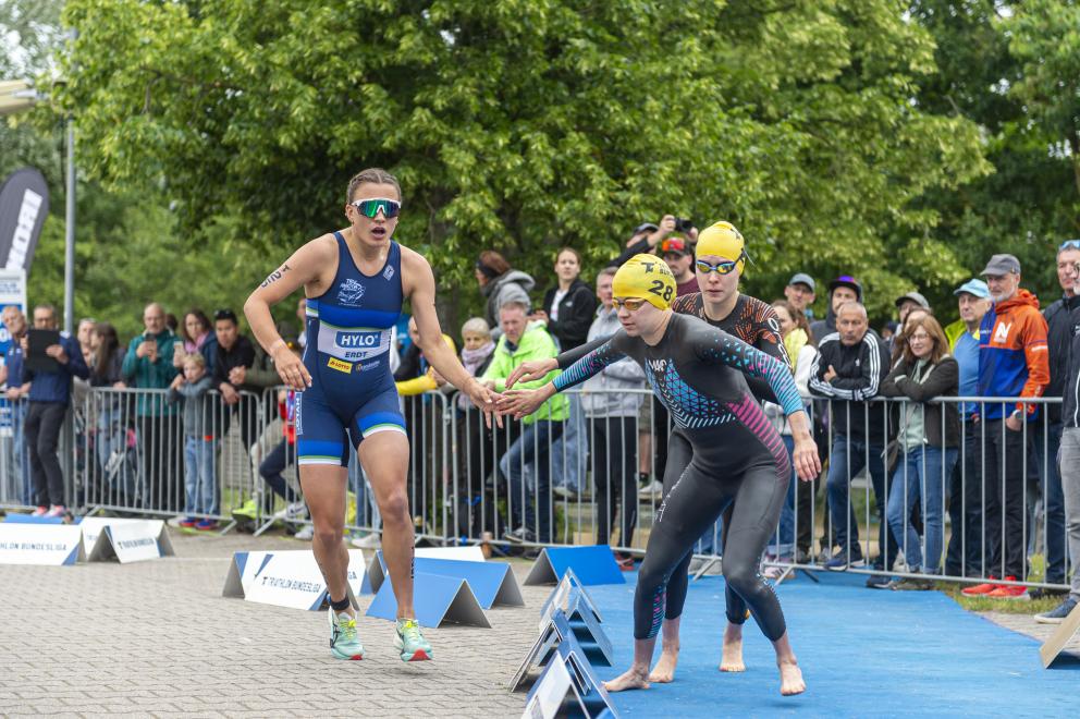 Athletin übergibt den Staffelstab per Handschlag an den nächsten