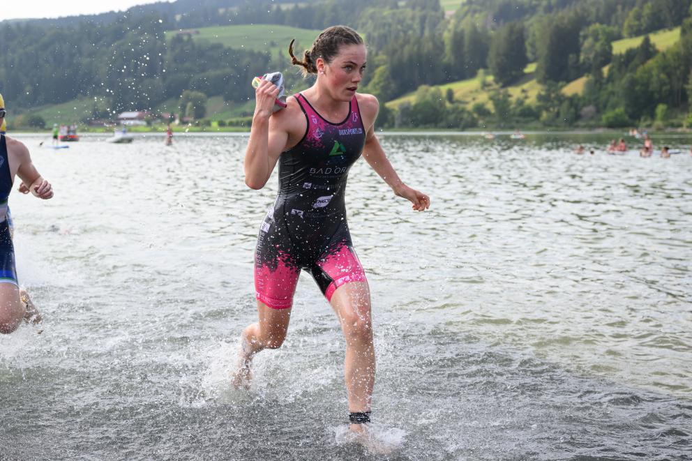 Athletin steigt aus dem Wasser und nimmt die Brille ab