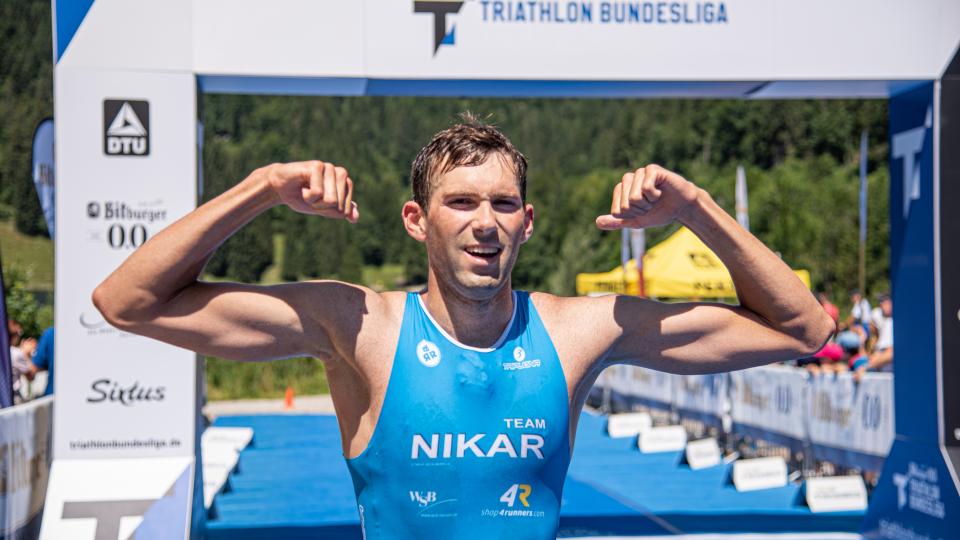 Athlet von Nikar Heidelberg posiert vor im Ziel mit seinen Muskeln. 