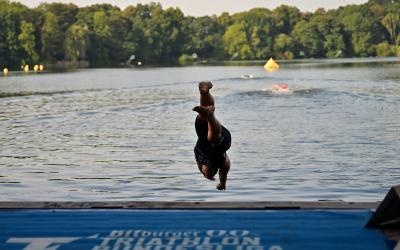 Ein Triathlet springt Kopfüber ins Wasser. 
