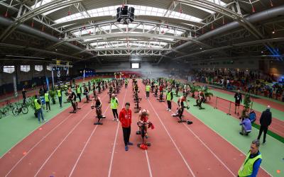 in einer Sporthalle treten mehrere junge Athleten auf Rollentrainern gegeneinander an