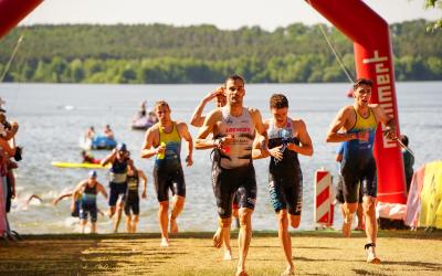 Athleten kommen aus dem Wasser und laufen den Strand hoch